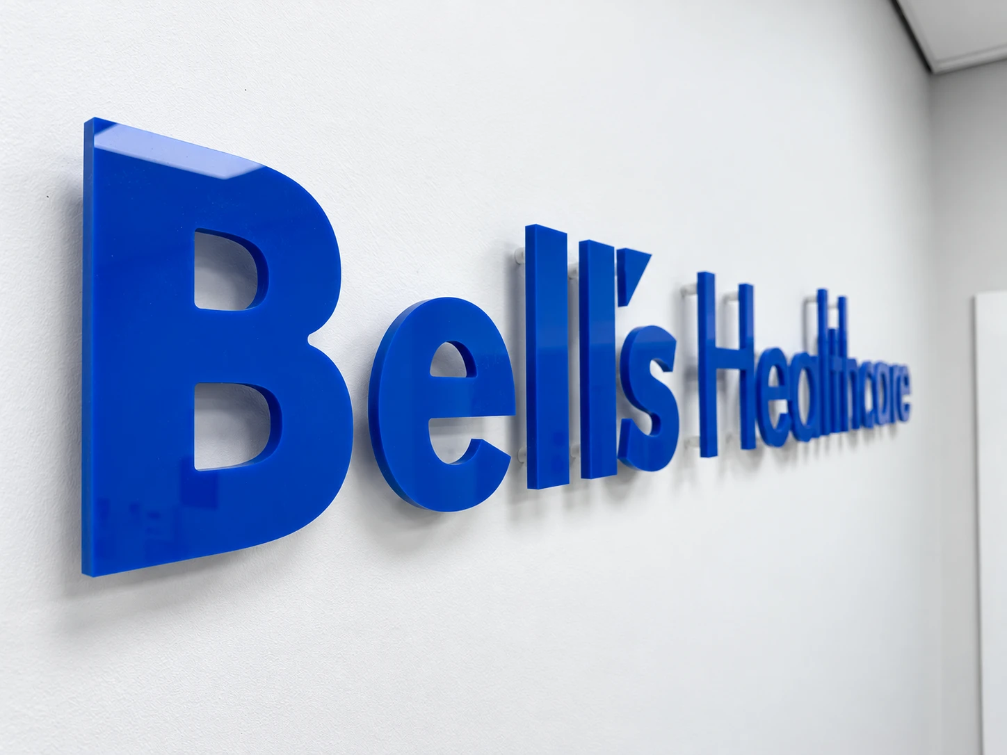 Close-up of blue Bell’s Healthcare acrylic letters with visible stand-off fixings