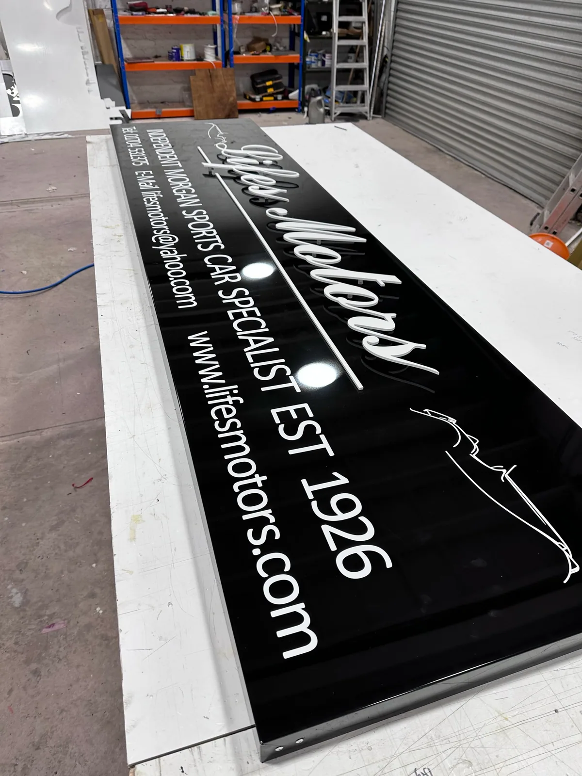 Black ACM sign tray with lettering and graphics
