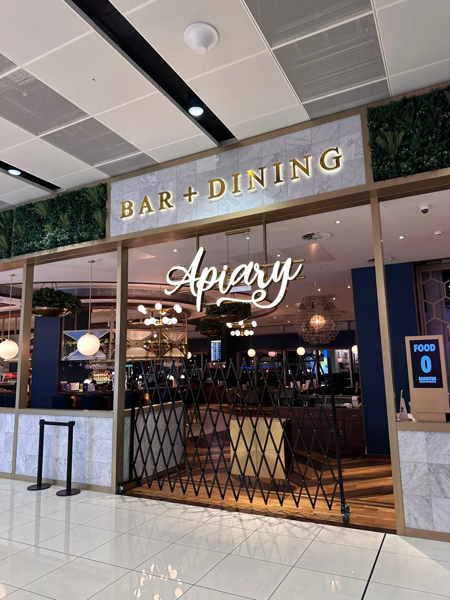 Illuminated Apiary script sign and Bar and Dining lettering at an interior entrance