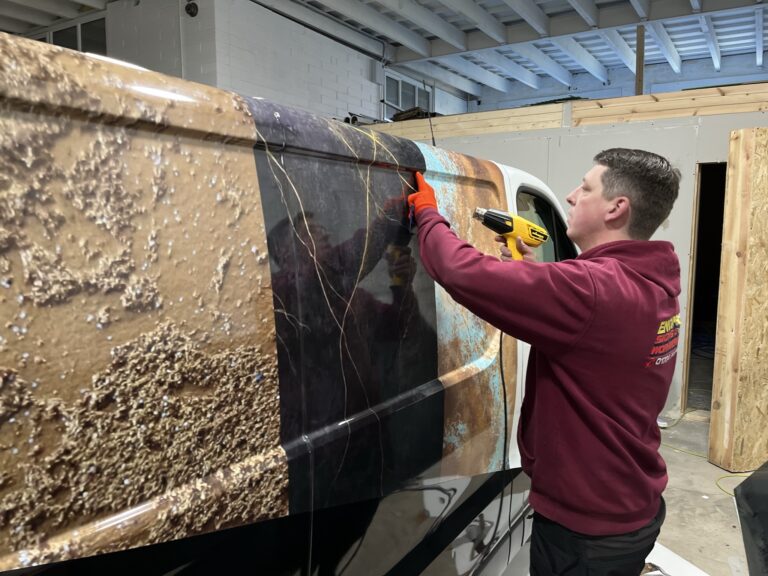 Enigma Signs installer fitting a full-colour printed vinyl wrap to a van