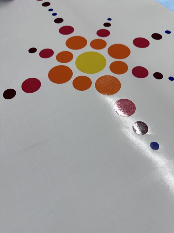 Colourful circular vinyl graphics arranged in a decorative pattern on a white surface