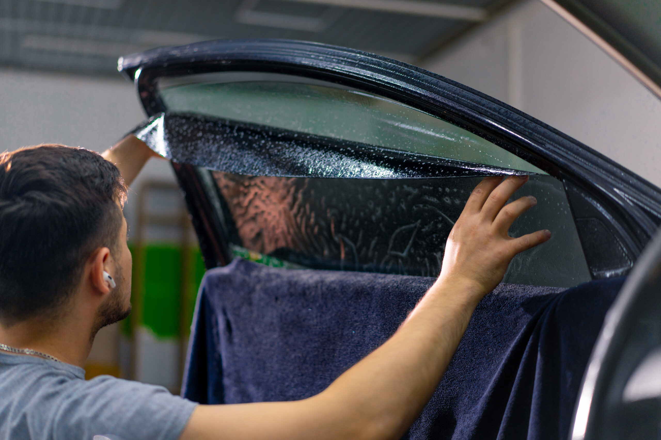 Male car service worker glue window tinting in luxury car detailing car repair the concept of love for cars and a protection