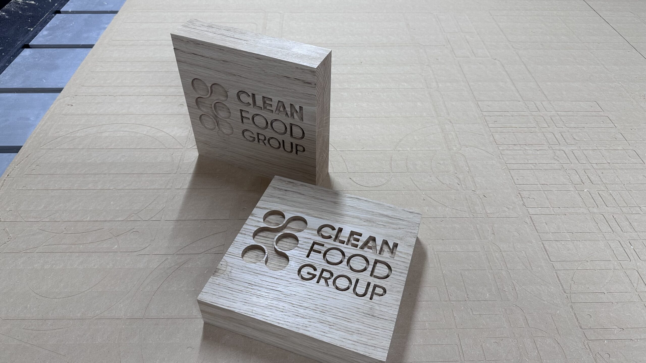 Two CNC-engraved oak logo blocks before waxing, one standing and one lying flat